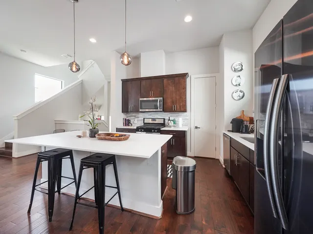 a kitchen with stainless steel appliances a table chairs refrigerator and microwave