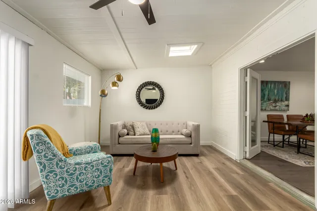 a living room with furniture a clock on wall and a window