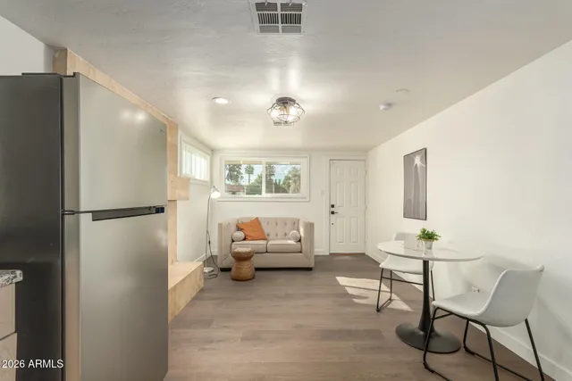 a living room with furniture and a refrigerator