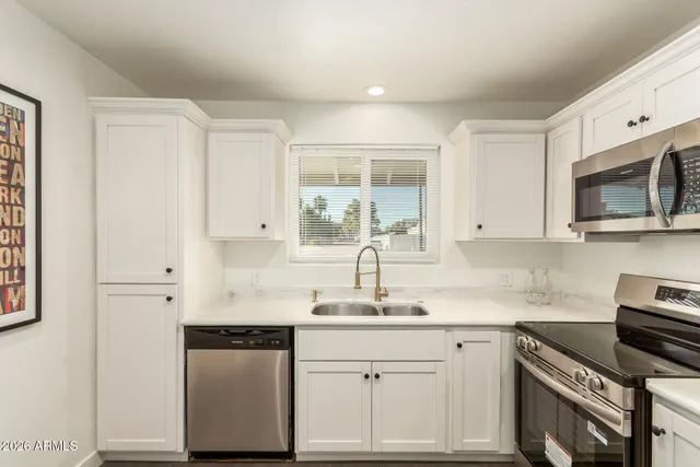 a kitchen with granite countertop white cabinets white stainless steel appliances with a sink and dishwasher