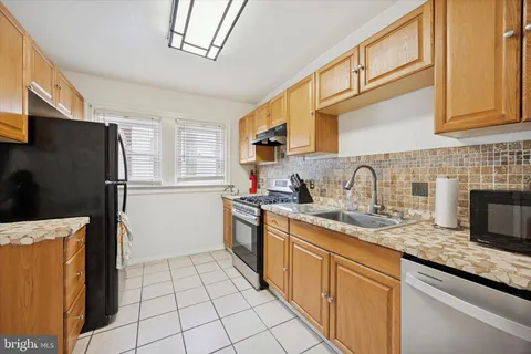 a kitchen with stainless steel appliances granite countertop a refrigerator a sink dishwasher a stove with wooden cabinets