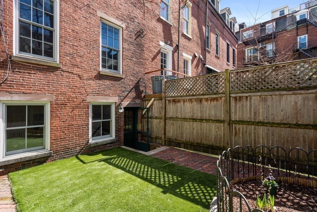 12 Cedar Street Boston, MA 02129 - Photo 11 of 23 a view of a brick house with a small yard and wooden fence