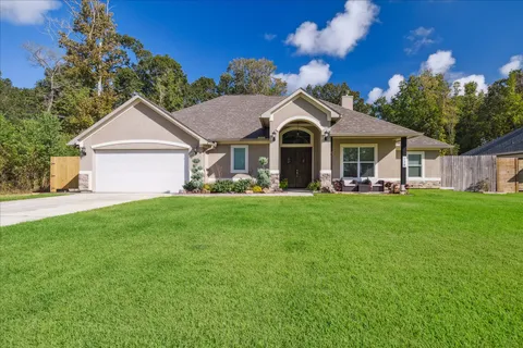a front view of a house with a garden and trees