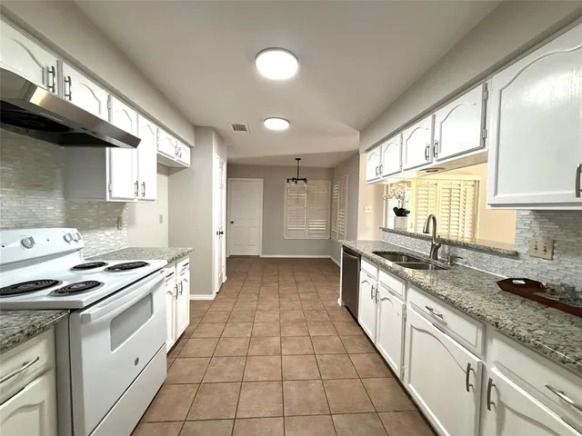 a large kitchen with stainless steel appliances granite countertop a stove a sink and a refrigerator