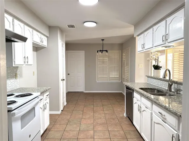 a kitchen with granite countertop a stove a sink and a refrigerator