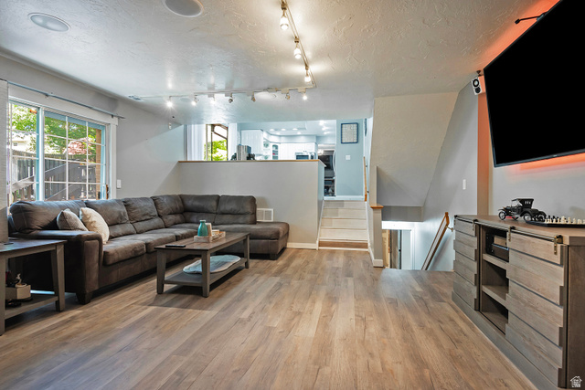 3310 Creek Road Salt Lake City, UT 84121 - Photo 20 of 49 Spacious main living area featuring wood-finish flooring, a patio door with exterior views, track lighting, recessed ceiling speakers, and a half-wall opening to an upper level