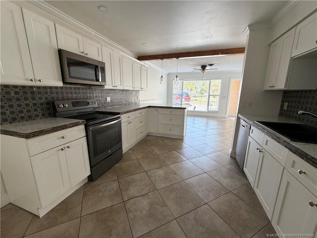 820 Northwest 10th Terrace Stuart, FL 34994 - Photo 4 of 21 a large kitchen with a stove a sink and a microwave