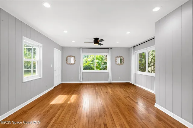 a view of empty room with wooden floor and fan