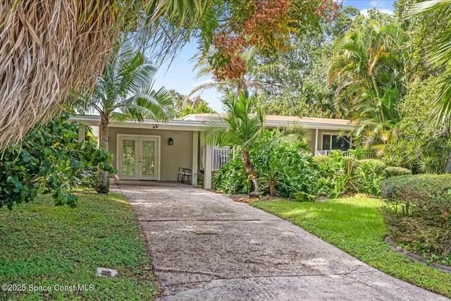a front view of a house with a yard and potted plants