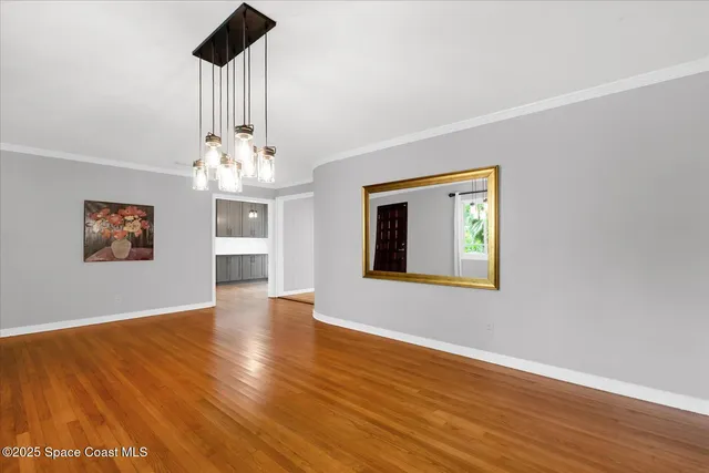 a view of an empty room with wooden floor and a ceiling fan