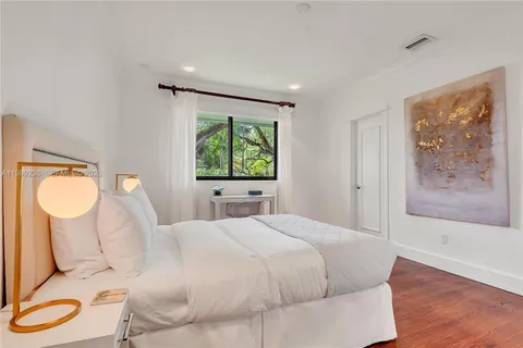 a spacious bedroom with a large bed and a flat tv screen