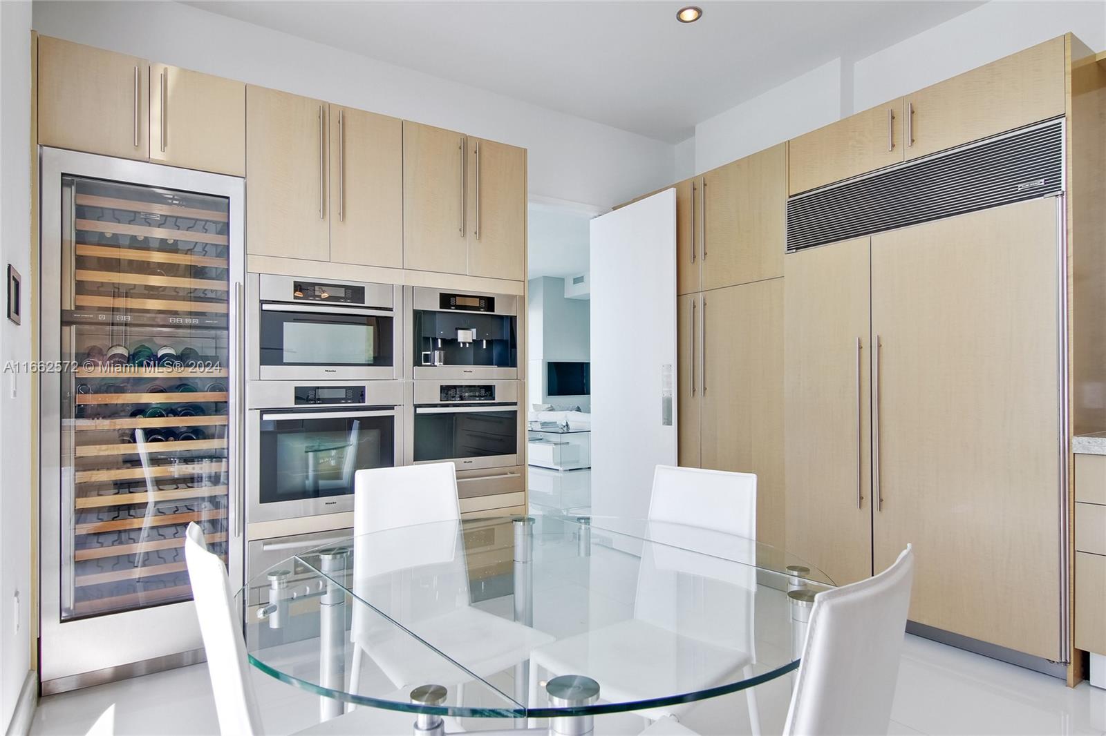 900 Brickell Key Boulevard, Unit PH3401 Miami, FL 33131 - Photo 14 of 58 a kitchen with stainless steel appliances kitchen island granite countertop a refrigerator a stove a microwave oven with white cabinets and wooden floor