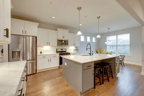 a kitchen with a refrigerator a stove a sink dishwasher a oven with white cabinets and wooden floor