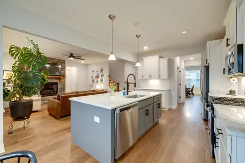 a large white kitchen with granite countertop a sink window and white stainless steel appliances