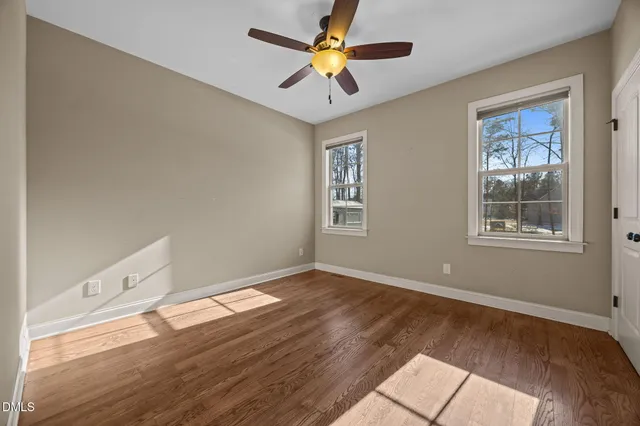 a view of an empty room with a window and wooden floor