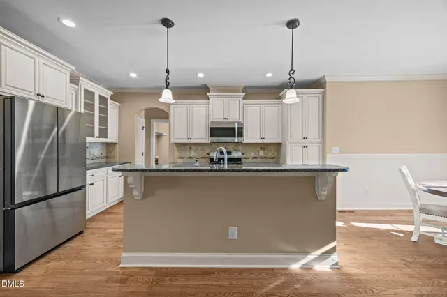 a kitchen with stainless steel appliances granite countertop a sink a stove a refrigerator and island with wooden floor