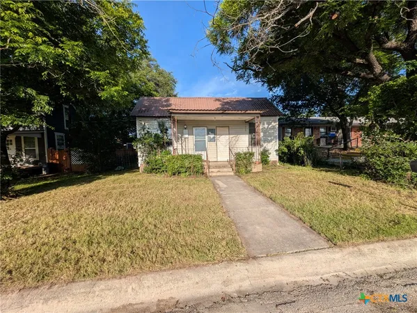 a front view of a house with a yard and potted plants