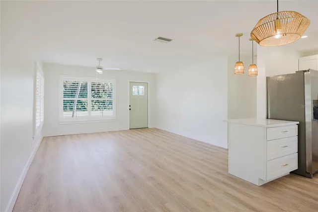 a view of empty room with wooden floor and kitchen