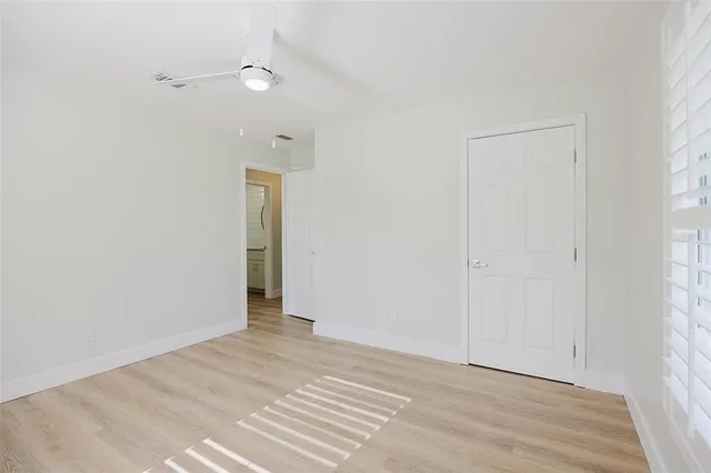 an empty room with windows and fan
