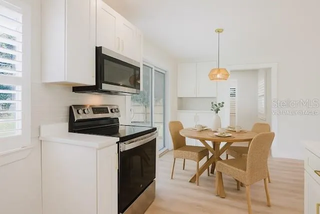 a kitchen with stainless steel appliances a table chairs and a refrigerator
