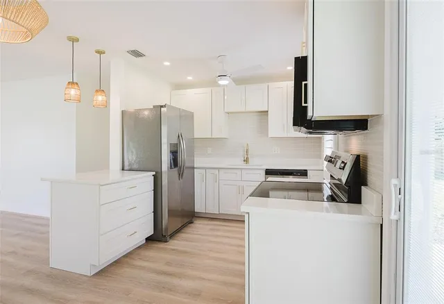 a kitchen with stainless steel appliances granite countertop a refrigerator a stove top oven a sink and dishwasher