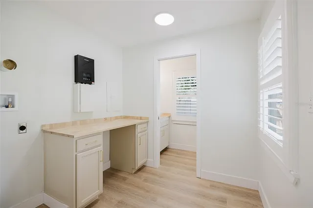 an empty room with wooden floor cabinet and windows