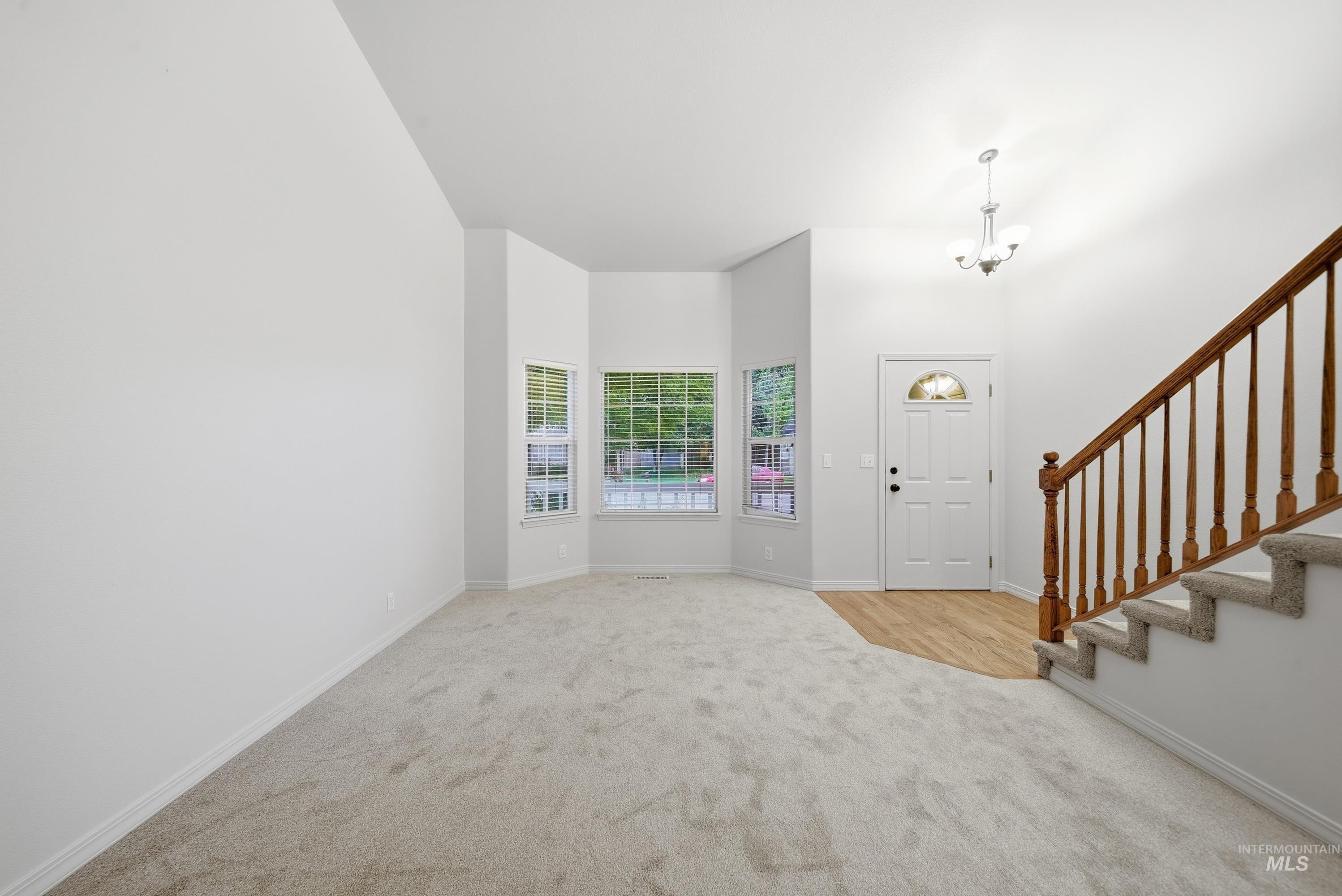 919 East Hawk Street Meridian, ID 83646 - Photo 3 of 31 Vaulted ceilings, bay windows, wood-finish flooring, staircase with wood railing, and an overhead chandelier