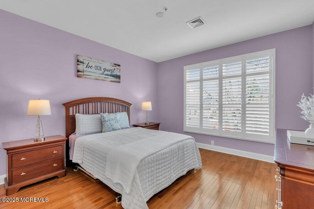 162 Main Street Manasquan, NJ 08736 - Photo 22 of 52 a bedroom with a bed and a lamp on dresser with wooden floor