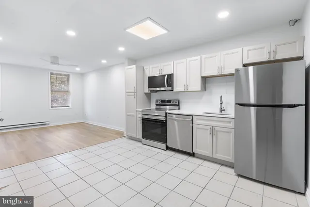 a kitchen with a refrigerator a stove top oven and white cabinets