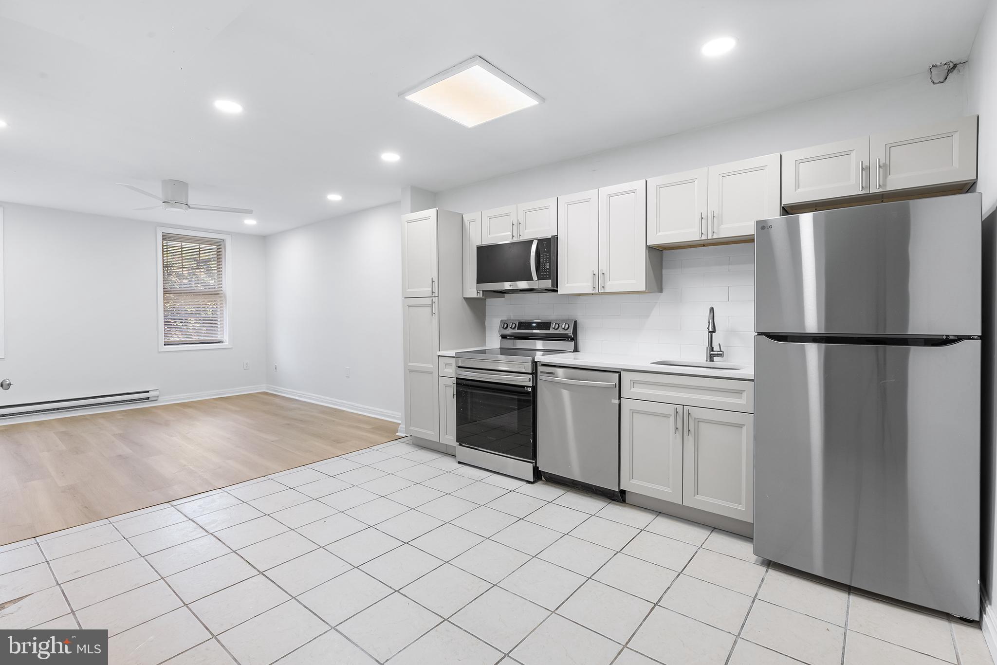 a kitchen with a refrigerator a stove top oven and white cabinets