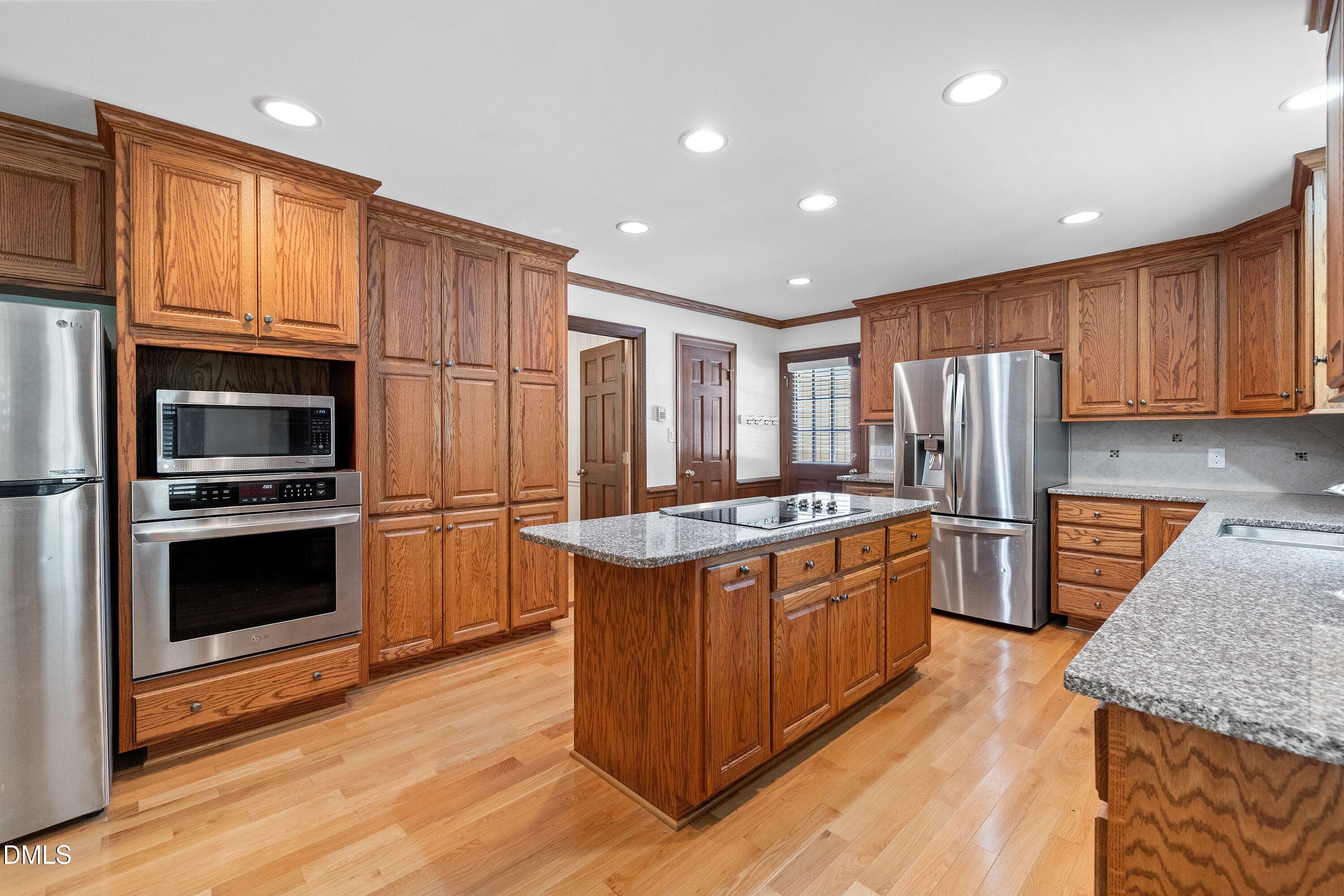 8133 Holly Forest Road Wake Forest, NC 27587 - Photo 16 of 50 a kitchen with stainless steel appliances granite countertop a refrigerator a stove and a wooden floors