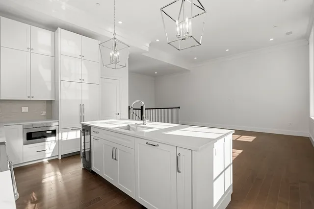 a kitchen with a sink dishwasher and white cabinets with wooden floor