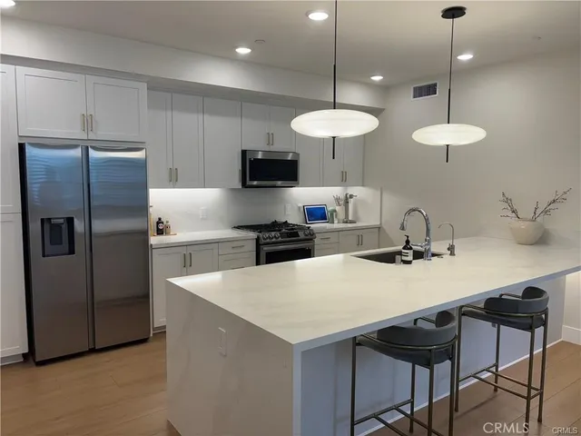 a kitchen with stainless steel appliances a table a sink and refrigerator