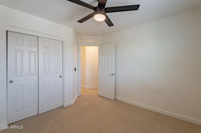 an empty room with closet and a chandelier fan