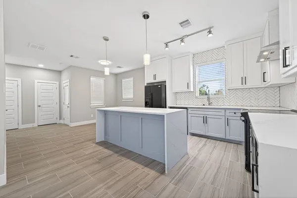 a kitchen with kitchen island white cabinets and stainless steel appliances