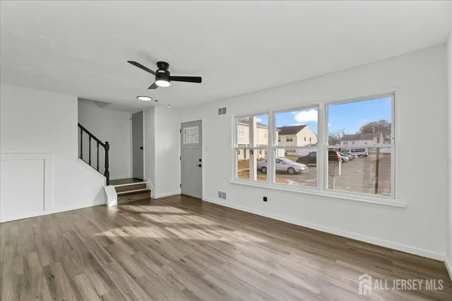 a view of empty room with wooden floor and fan