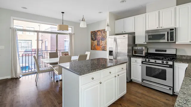 a kitchen with stainless steel appliances granite countertop a stove a refrigerator a microwave a sink and white cabinets with wooden floor