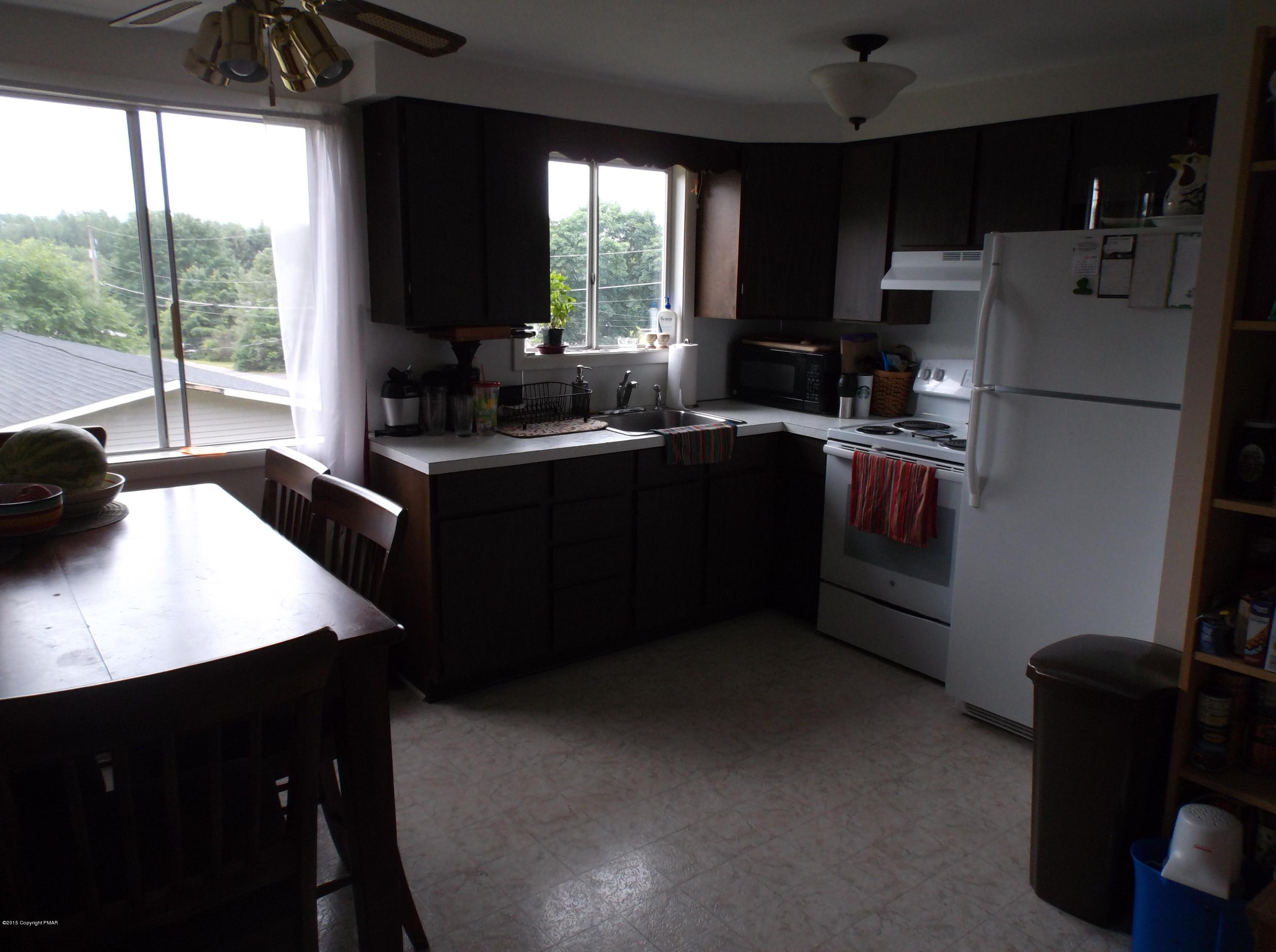 3430 Walnut Road Kunkletown, PA 18058 - Photo 3 of 16 a kitchen with a refrigerator a sink a stove a dining table and chairs