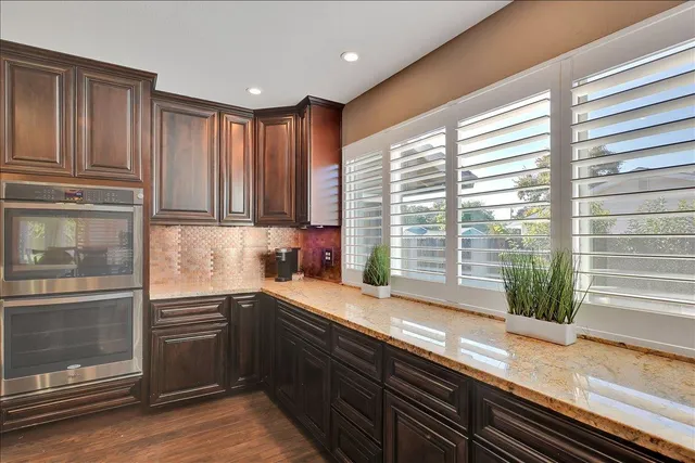 a kitchen with kitchen island granite countertop a refrigerator a sink dishwasher and wooden cabinets with wooden floor