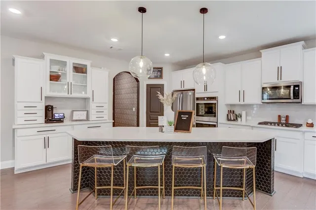 a kitchen with stainless steel appliances a kitchen island hardwood floor sink stove and white cabinets