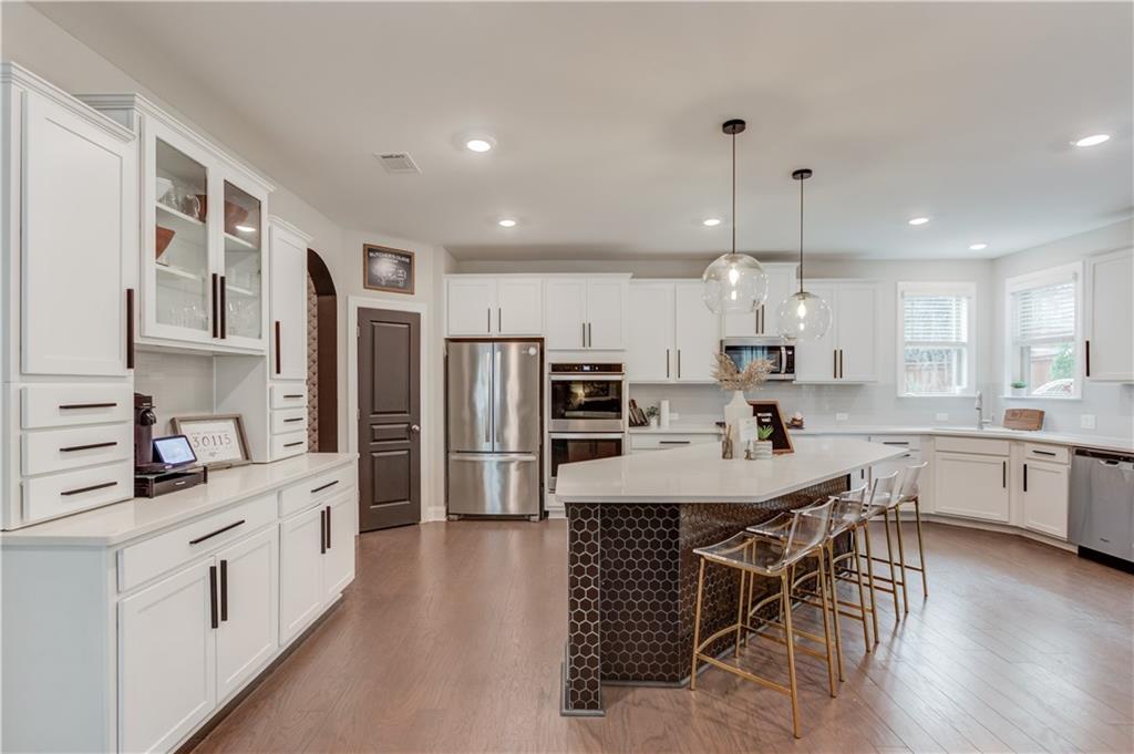 542 Flyingbolt Run Canton, GA 30115 - Photo 15 of 55 a kitchen with stainless steel appliances a kitchen island hardwood floor sink stove and white cabinets