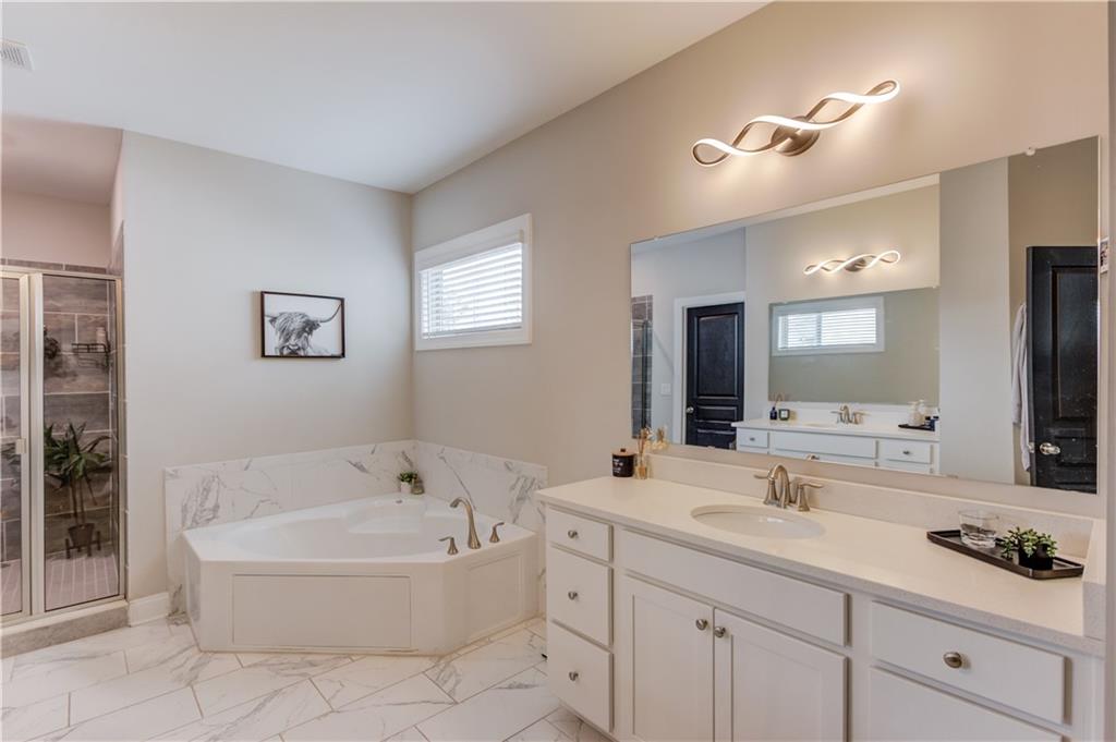 542 Flyingbolt Run Canton, GA 30115 - Photo 26 of 55 a bathroom with a bathtub a double vanity sink and mirror