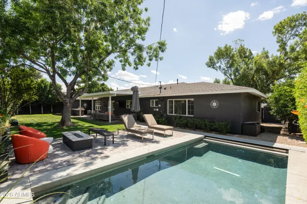 a view of a house with backyard sitting area and swimming pool