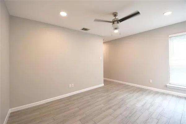 an empty room with wooden floor and a ceiling fan