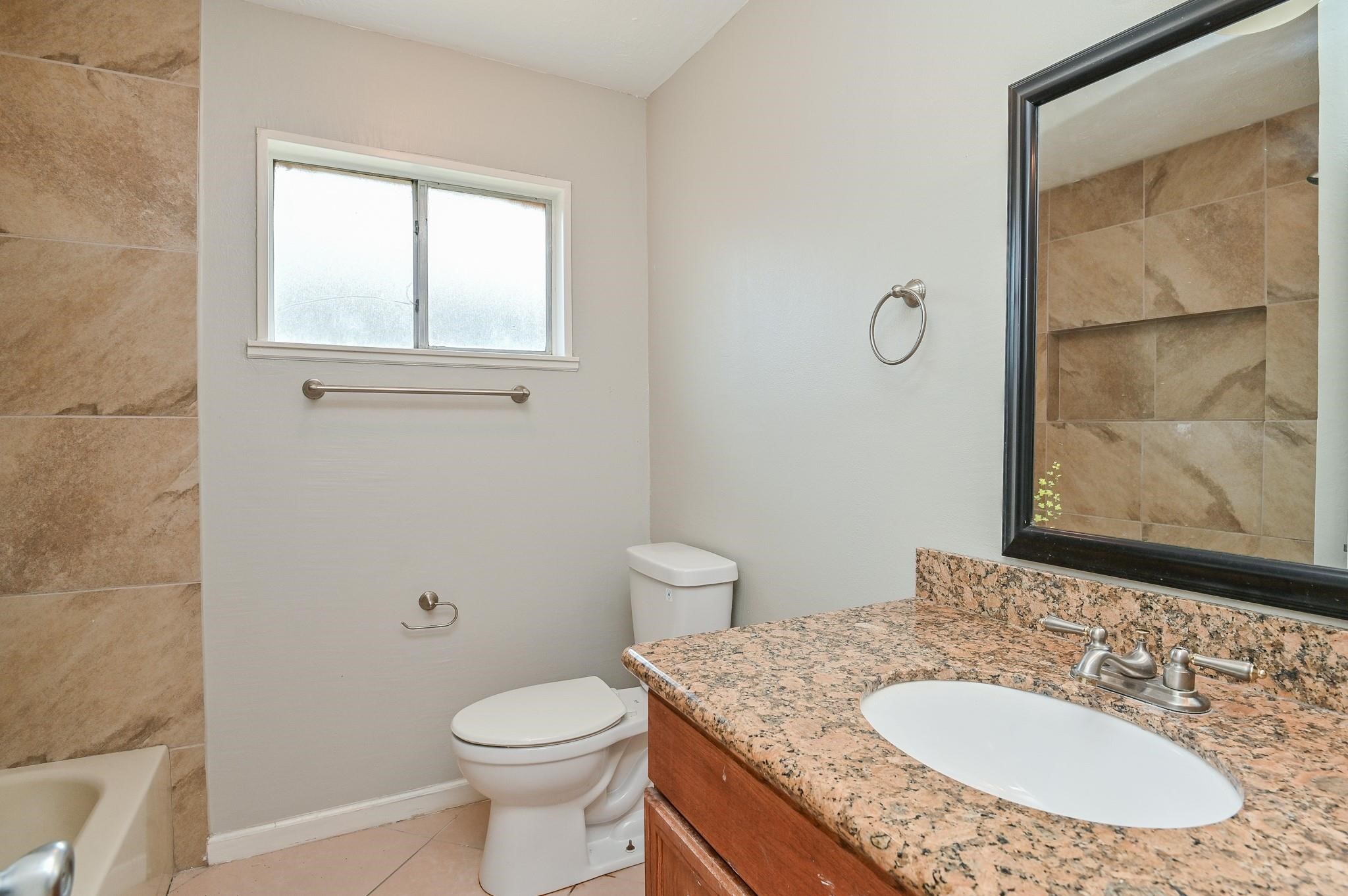 10019 Overview Drive Sugar Land, TX 77498 - Photo 23 of 30 a bathroom with a granite countertop toilet a sink and a mirror