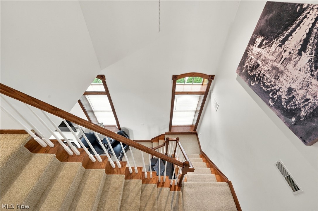 42764 Russia Road Elyria, OH 44035 - Photo 28 of 50 Carpeted staircase with wood-finish risers and handrails, white spindles, and vaulted ceilings