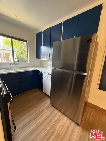 a kitchen with kitchen island wooden floors and refrigerator
