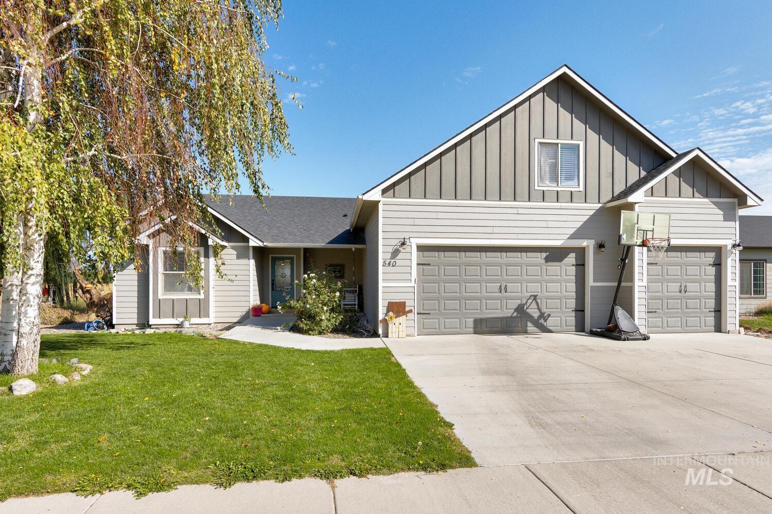 View of front of home featuring board and batten siding, a front yard, concrete driveway, and roof with shingles
