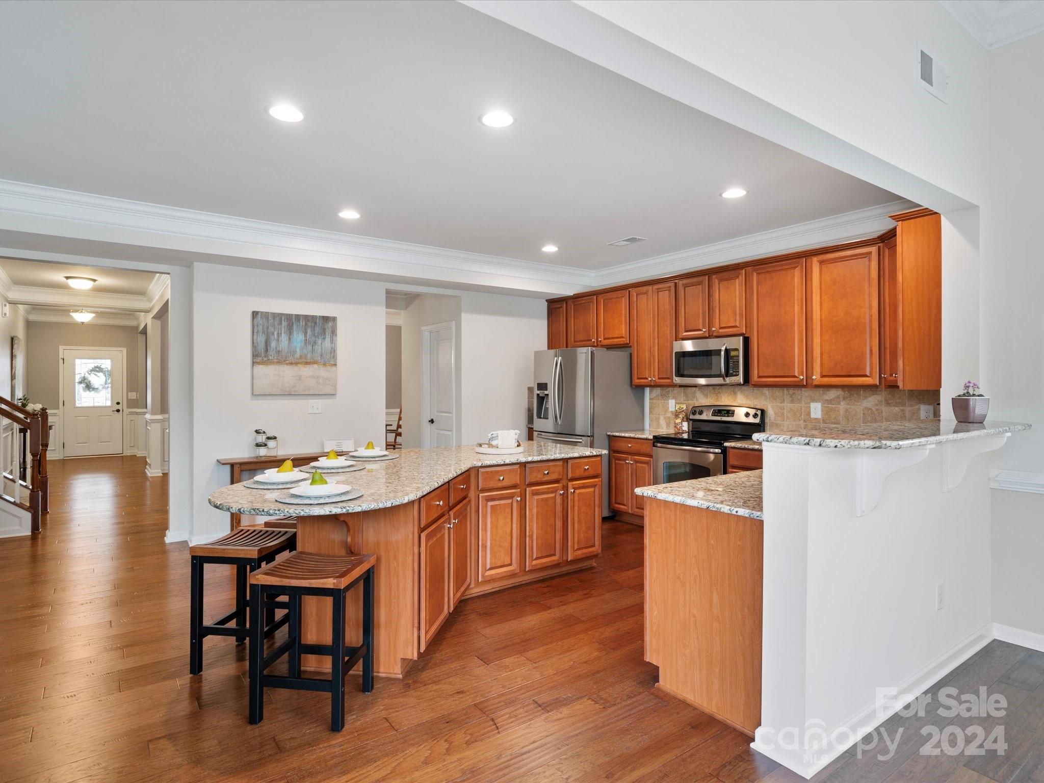 1617 Ridgehaven Road Waxhaw, NC 28173 - Photo 10 of 47 a kitchen with stainless steel appliances granite countertop a stove top oven a sink dishwasher a dining table and chairs with wooden floor