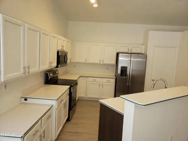 a kitchen with a sink a refrigerator and white cabinets